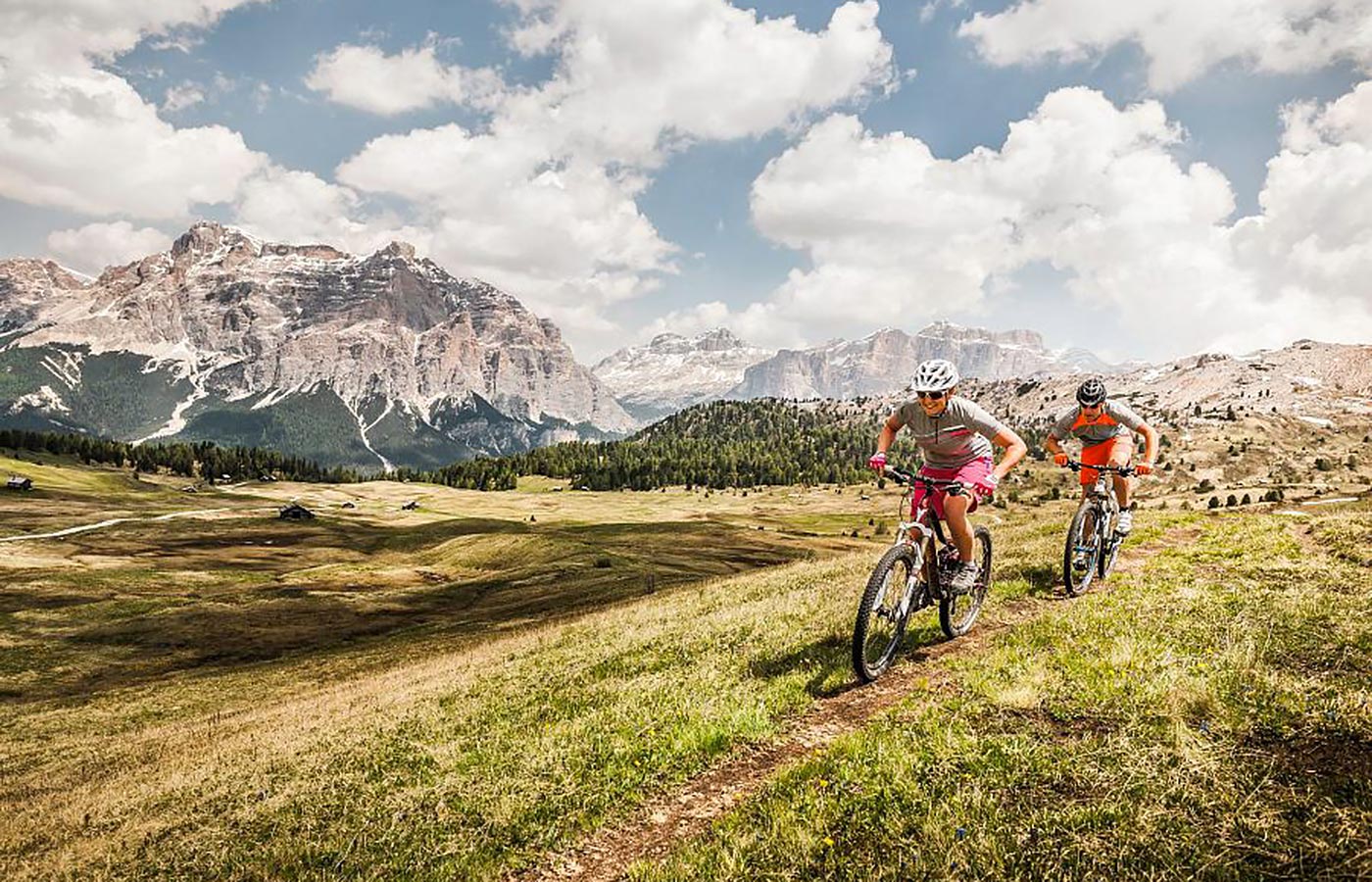 Mountainbiker su un prato con le Dolomiti sullo sfondo