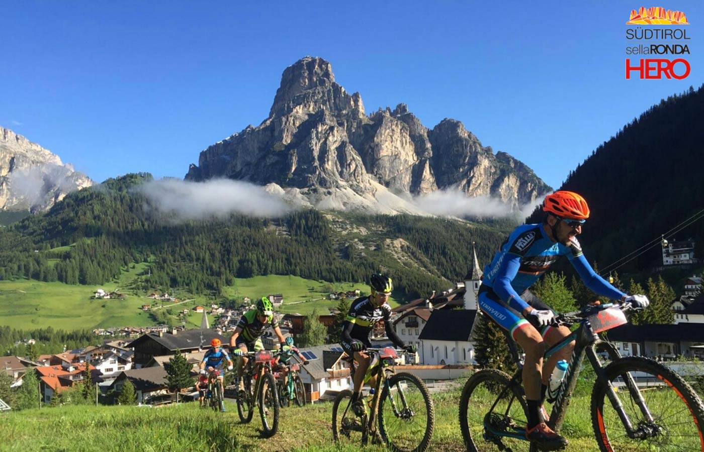 Mountainbiker su un prato con montagne sullo sfondo