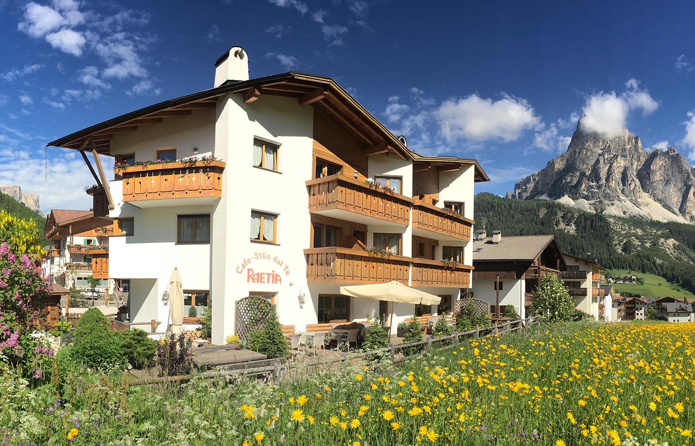 Blick auf das Garnì Raetia auf der Blumenwiese mit den Dolomiten im Hintergrund